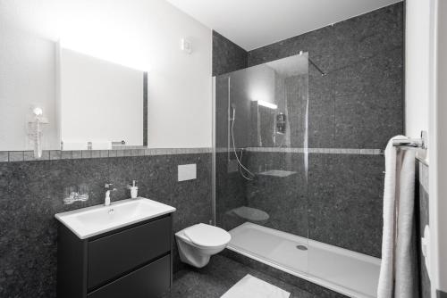 a black and white bathroom with a toilet and a shower at BetweenLakes Studio ground floor west in Interlaken