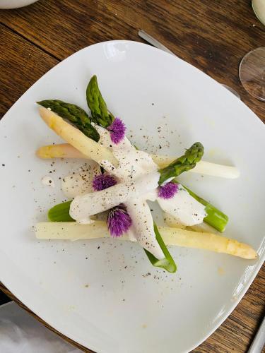 une plaque blanche avec une fleur sur une table dans l'établissement La Maison des Ifs Terracotta, à Mamers