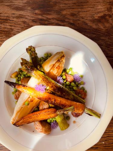 une assiette de nourriture avec des carottes et des petits pois sur une table dans l'établissement La Maison des Ifs Terracotta, à Mamers