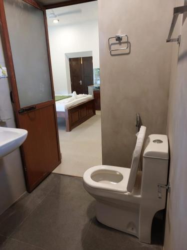 a bathroom with a white toilet and a sink at Das Haus Villa & Restaurant in Unawatuna
