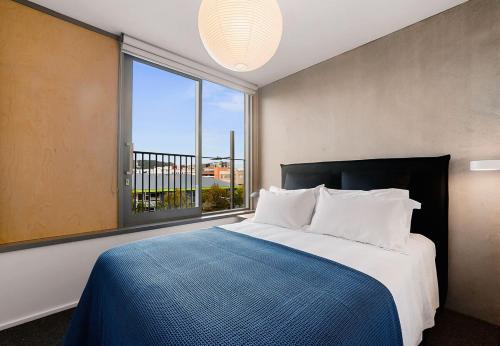 a bedroom with a large bed and a large window at Urban Chic Townhouse - 2BR Modern Industrial Vibe in Wellington