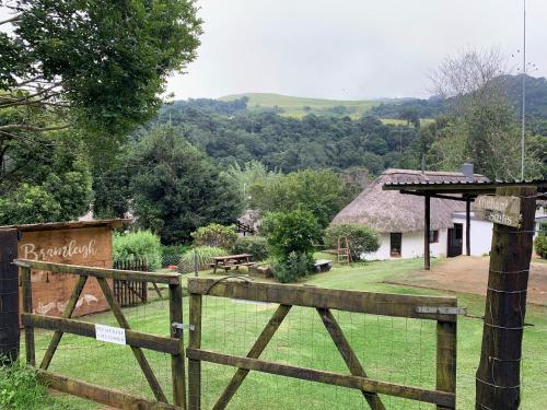 a wooden fence in front of a thatched house at Bramleigh Farm in Nottingham Road