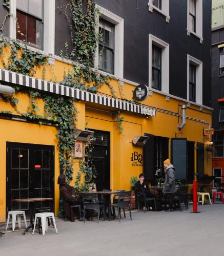 a yellow building with people sitting at tables outside at Urban Chic Townhouse - 2BR Modern Industrial Vibe in Wellington