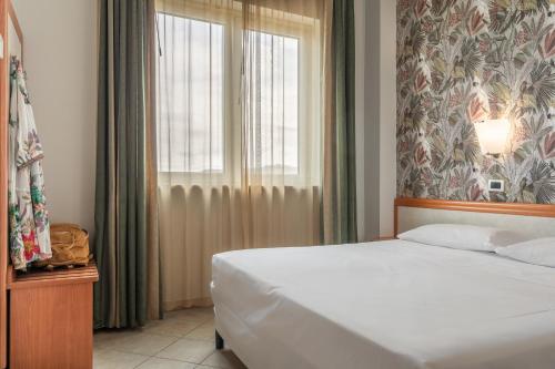 a bedroom with a white bed and a window at Hotel Prestige in Montesilvano