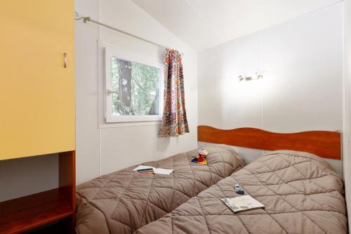 a bedroom with a bed with books and a window at Capfun Fort Bedmar in Sint-Gillis-Waas