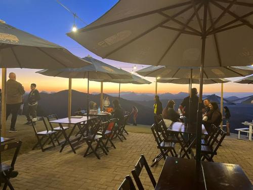 a group of people sitting at tables under umbrellas at Chalé na Rampa - Hospedagem no Caravaggio in Santa Teresa