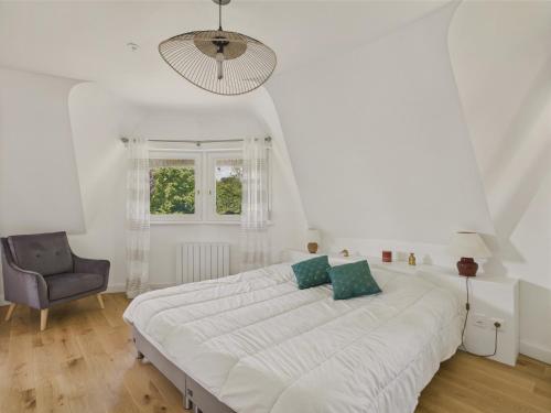 une chambre blanche avec un grand lit et une chaise dans l'établissement Piscine chauffée, Grand jardin, maison pour 8, à Pleuven
