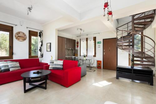 a living room with a red couch and a spiral staircase at Frida & Rosa by halu! - Villas in Kriopigi in Kriopigi