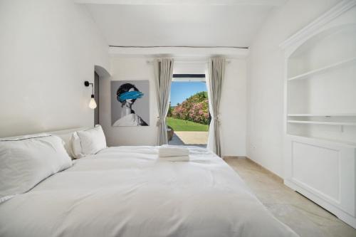 un grand lit blanc dans une chambre avec une fenêtre dans l'établissement Villa Tournels Luxury, à Ramatuelle