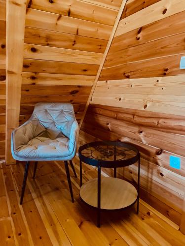 a room with a chair and a stool in a wooden wall at Guest House LENA in Žabljak
