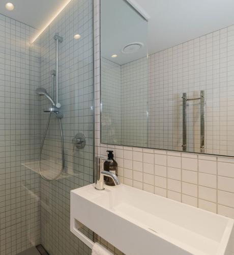 a bathroom with a sink and a shower with a mirror at City Central Retreat - Sleek Studio Living in Wellington