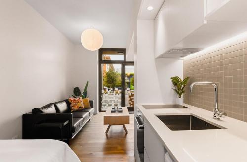 a kitchen with a sink and a couch in a room at City Central Retreat - Sleek Studio Living in Wellington
