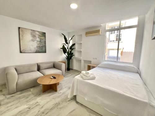ein weißes Schlafzimmer mit einem Bett und einer Couch in der Unterkunft La Plaza City Center & Beach Cozy Studios in Fuengirola