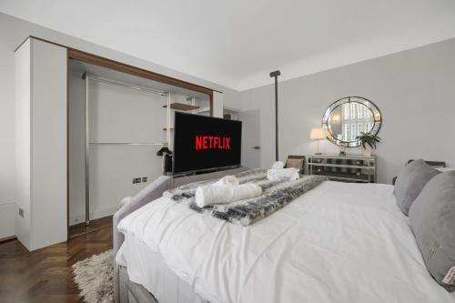 a white bed in a room with a tv at Modern & Unique - Central & Beach Access in Swansea