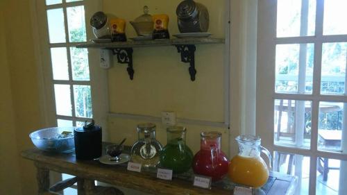 a table with different colored glass vases on it at Pousada D'amoras in Conservatória