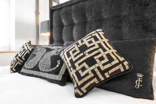 a bed with black and gold pillows on it at Modern & Unique - Central & Beach Access in Swansea