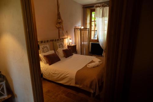 a bedroom with a bed with white sheets and a window at Les Jardins des Soussilanges in Céron