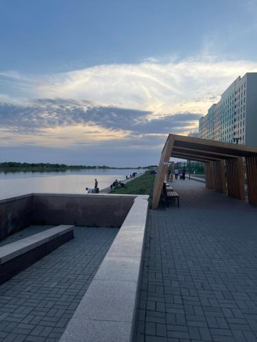 ein Gehweg mit Bänken und Blick auf das Wasser in der Unterkunft Kolsay in Kirovo