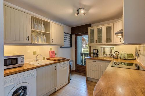 une cuisine avec des armoires blanches et une laveuse et une sécheuse dans l'établissement APARTMENT CHAMOUNY - Alpes Travel - Chamonix - Sleeps 8, à Chamonix-Mont-Blanc
