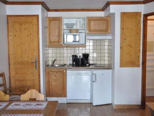 une cuisine avec des appareils électroménagers blancs et des armoires en bois dans l'établissement Appartement cosy 4 pers. avec balcon et WiFi - FR-1-263-392, à Valloire