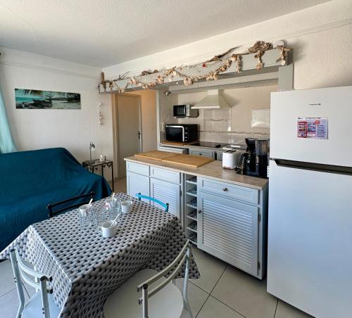 une cuisine avec une table et un réfrigérateur blanc dans l'établissement Superbe T2 face mer 4EST402, au Barcarès