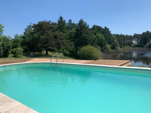 une grande piscine avec un lac en arrière-plan dans l'établissement Le Manoir de Pierre Levée, The Originals Collection, à Tournon-Saint-Martin