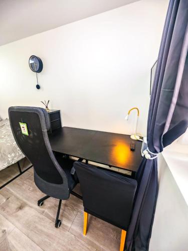 a black desk with a chair and a bed at Ensuite Double Room with Kitchen in Hayes
