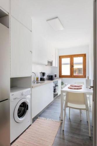 a white kitchen with a table and a washing machine at Charming place near the beach Casa Checha in Candelaria