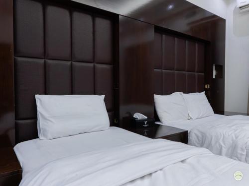 two beds in a hotel room with white sheets and pillows at Greenland Farm in Dubai