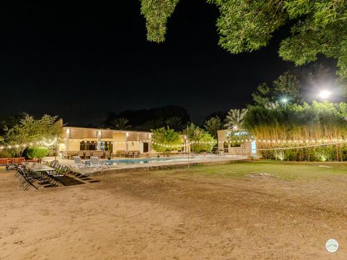 a building with a lot of tables and chairs at night at Greenland Farm in Dubai