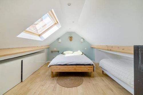 - une chambre mansardée avec un lit et une lucarne dans l'établissement Large Maison de ville 5 chambres avec jardin saint maur proche centre ville lille, à La Madeleine