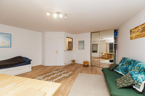 un salon avec un canapé vert et un lit dans l'établissement Apartment near Buttes Chaumont, à Paris