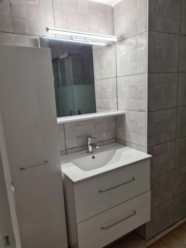 une salle de bain blanche avec un lavabo et un miroir dans l'établissement Appartement Saint Cyprien plage réservable du samedi au samedi les mois de Juillet et Aout, à Saint Cyprien Plage