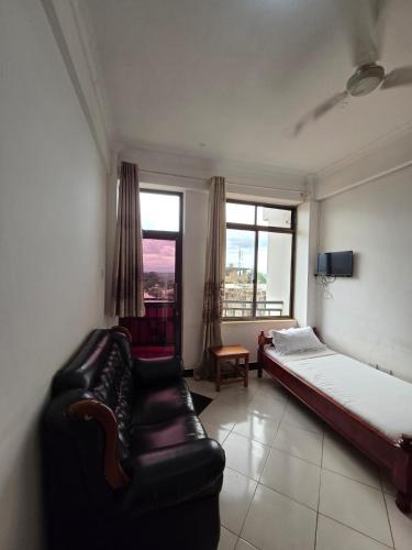 a bedroom with a couch and a bed and a window at Tulivu Urban - Twiga Hotel in Moshi