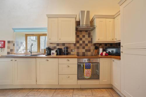 una cucina con mobili bianchi e una stufa di Beautiful Barn Conversion with Games Room a Ilfracombe