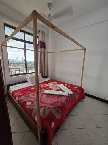 a bedroom with a canopy bed with a red comforter at Tulivu Urban - Twiga Hotel in Moshi