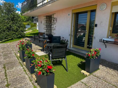 - une terrasse avec une table, des chaises et des fleurs dans l'établissement Le Myosotis, Perle du Haut Doubs, à Malbuisson