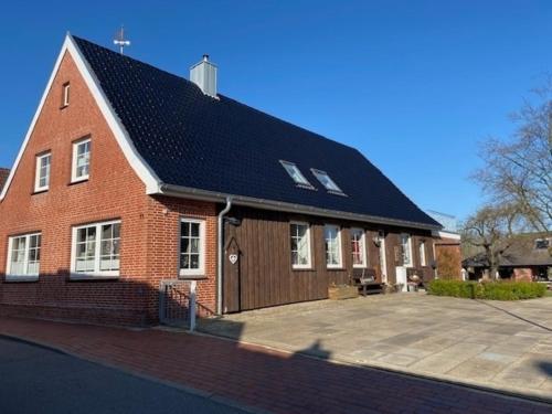 ein großes rotes Backsteingebäude mit schwarzem Dach in der Unterkunft Emily's in Tönning