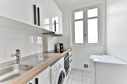 une cuisine blanche avec un évier et un comptoir dans l'établissement Appartement Arc de Triomphe - Neuilly - II, à Neuilly-sur-Seine