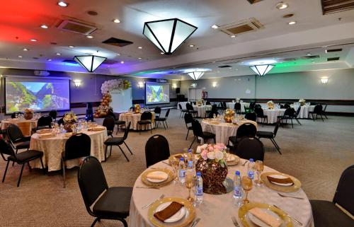 a banquet hall with tables and chairs and a screen at Holiday Inn - Harare by IHG in Harare