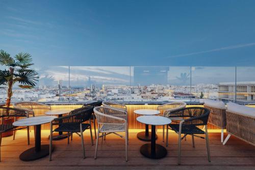 a balcony with tables and chairs and a view of a city at Exe Casablanca in Casablanca