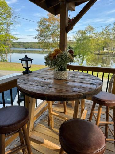 a wooden table on a deck with chairs and a lake at Cozy lake house in Nassau