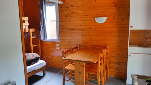 Cette chambre est dotée d'un mur en bois avec une table et des chaises. dans l'établissement Camping Les Oyats, à Soulac-sur-Mer