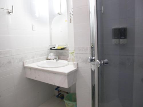a white bathroom with a sink and a shower at Hoa Phat Hotel & Apartment in Ho Chi Minh City