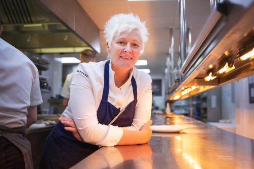 a woman sitting at a counter in a kitchen at Northcote in Langho
