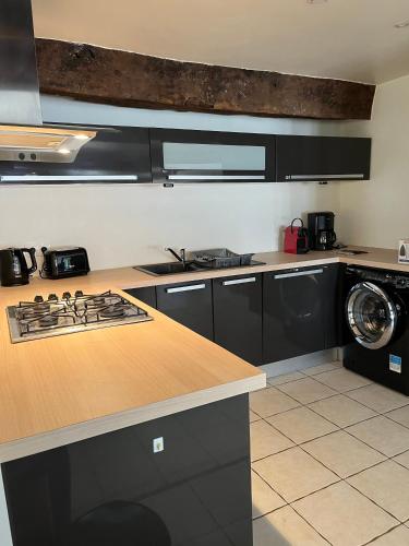 Il comprend une cuisine équipée d'une cuisinière. - un four supérieur à côté d'un lave-linge dans l'établissement Séjour de charme au cœur de Pontrieux Appartement, à Pontrieux