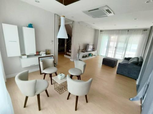 ein Wohnzimmer mit weißen Stühlen und einem Sofa in der Unterkunft The Lanna Lagoon เดอะลานนา ลากูน in Chiang Mai