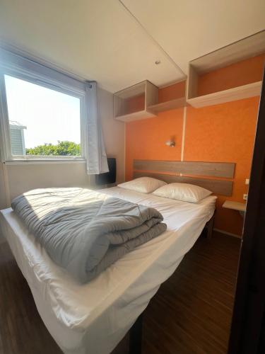 a large bed in a room with a window at Mobilhome G05A in Boofzheim
