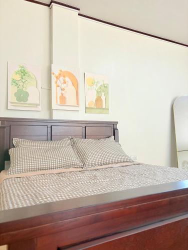 a bedroom with a wooden bed with two pictures on the wall at Casita del Mabini in Mabini