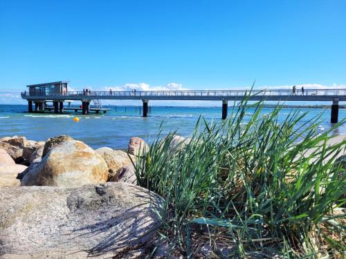 a pier in the water with rocks and grass at Preiswertes Mini-Appartement ideal für eine Nacht in Scharbeutz